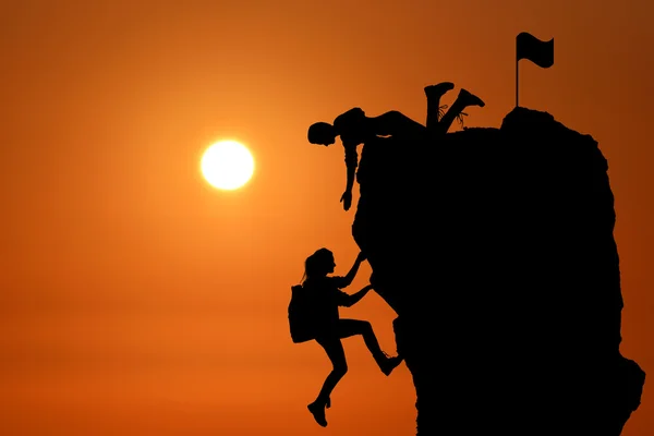 The joint work teamwork of two people man and girl travelers help each other on top of a mountain climbing team, a beautiful sunset landscape. — Stock Photo, Image