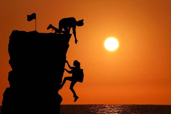 Совместная работа команды из двух человек мужчина и девушка путешественники помогают друг другу на вершине альпинистской команды, красивый пейзаж заката
.