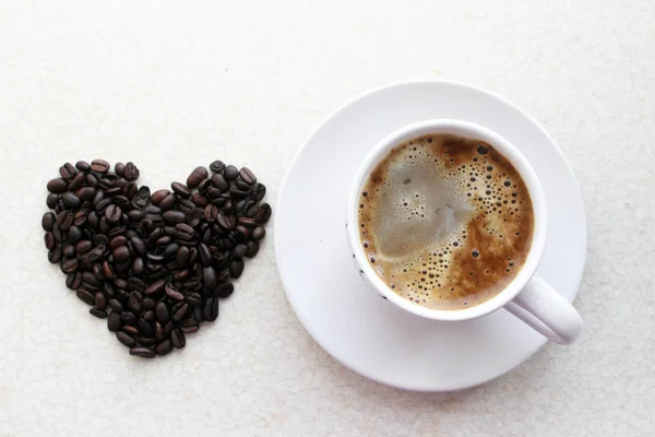 Καρδιά καφέ δίπλα σε ένα φλιτζάνι καφέ — Φωτογραφία Αρχείου