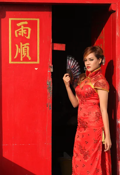 Mulher de vestido chinês em pé na porta vermelha — Fotografia de Stock