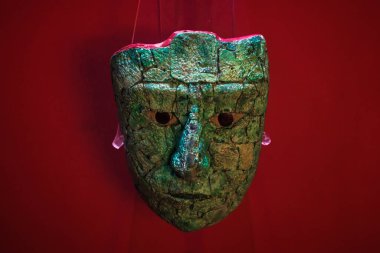 Palenque, Chiapas, Meksika - 22 Mayıs 2019: Palenque arkeoloji sahasındaki müzede kırmızı arka planda yeşim taşlı Maya maskesi heykeli