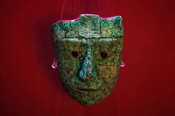 Palenque, Chiapas, Meksika - 22 Mayıs 2019: Palenque arkeoloji sahasındaki müzede kırmızı arka planda yeşim taşlı Maya maskesi heykeli