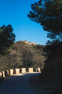 Doğal parktaki ağaçlar arasındaki güneşli yürüyüş yolu Serra Gelada dağdaki deniz fenerine doğru, Albir, Costa Blanca, İspanya