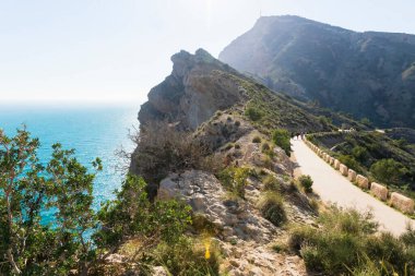 İnsanlar, Albir, Costa Blanca, İspanya 'daki' Serra Gelada 'parkında okyanus boyunca dik uçurumlar boyunca uzanan yolda yürüyorlar.
