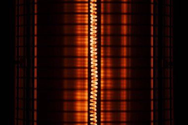Close up of an orange red electric heater coil with grill protection