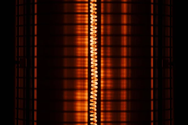 Close up of an orange red electric heater coil with grill protection