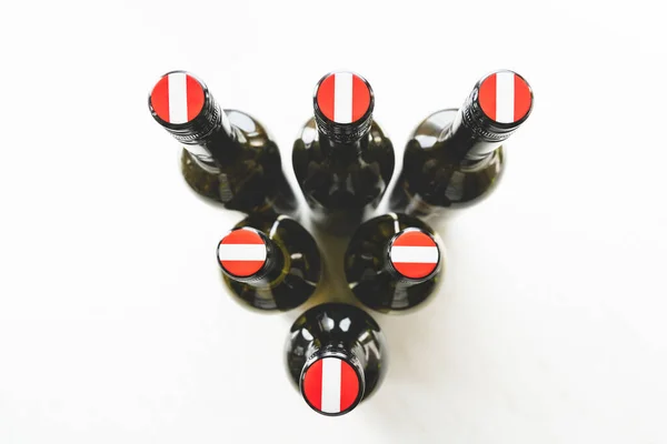 Wine bottles with Austrian flags on the screw caps from the top arranged in a triangle in bright light