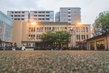 Kyoto, Japonya - 17 Eylül 2017: Ziyaretçiler ve öğrenciler, akşam saatlerinde Uluslararası Manga Müzesi 'nin arka bahçesinde oturmuş kitap okuyorlar.