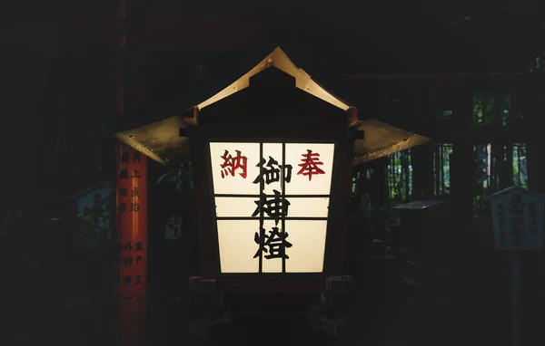 Enlightened Japanese lantern in front of torii gate at Nonomiya Shrine in the evening in Kyoto, Japan
