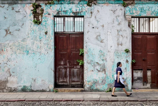 グアテマラのアンティグア グアテマラ 2018年4月25日 地元のメイドが壊れた壁から木のドアや植物が成長している古い放棄された植民地時代の建物に沿って歩く — ストック写真