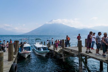 San Marcos la Laguna, Guatemala - 29 Mart 2018: Yanardağ manzaralı motorlu teknelerle iskeleye gelen insanlar