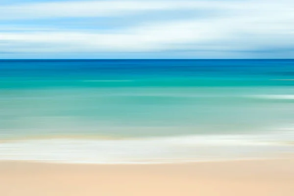 A seascape abstract with panning motion combined with a long exposure.  Image displays soft, pastel colors in a retro style.