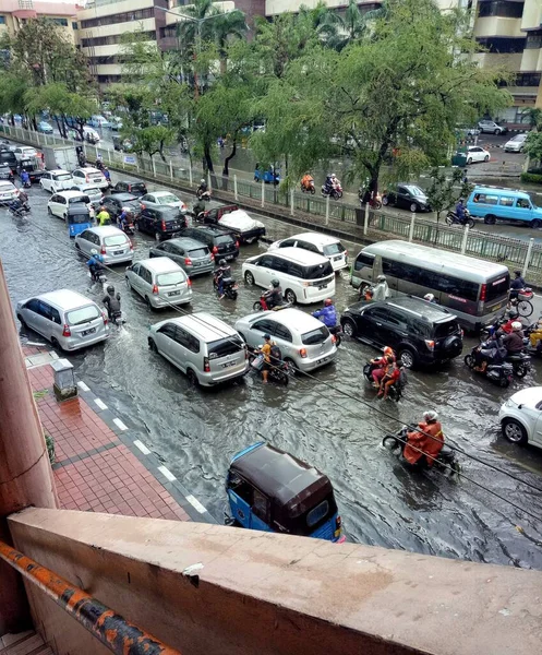 Mevsimsel seller işlek bir yolda trafiğe neden oluyor. Arabalar, Motorlu Bisikletler ve Sel Yolu 'nda Bajaj Seyahati. Endonezya 'da Yıllık Doğal Afet Suyu. Jakarta 'da sel.