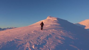 Kışın gün batımında zirvelerde yürüyüş yaparak nefes kesici bir dağ manzarası.