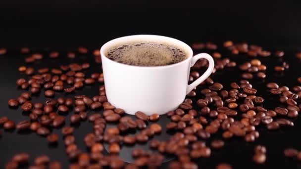 黒を背景にコーヒーとロースト豆の白いカップ — ストック動画