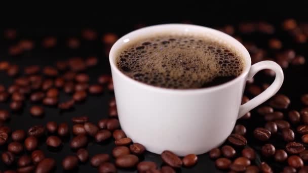 黒を背景にコーヒーとロースト豆の白いカップ — ストック動画
