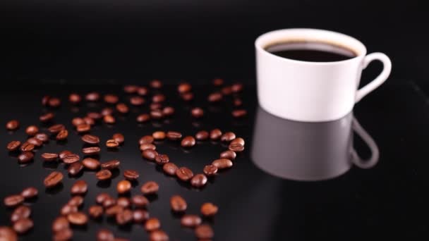 Weiße Kaffeetasse und herzförmige geröstete Bohnen auf schwarzem Hintergrund