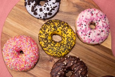 Ahşap masa ve pembe arka planda donut karışımı.