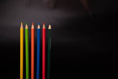 Siyah arkaplanda renkli kalem grubu