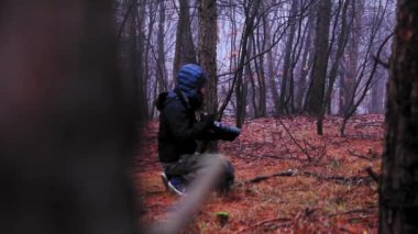 Sonbahar mevsiminde sisli bir ormanda renkli yapraklarla fotoğraf çeken bir adam.
