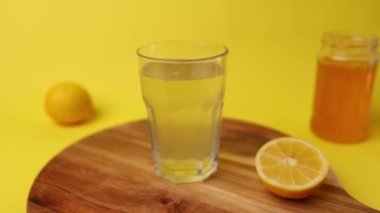 Tahta masada limonatalı bir bardak ve limon ve ballı sarı arka plan.