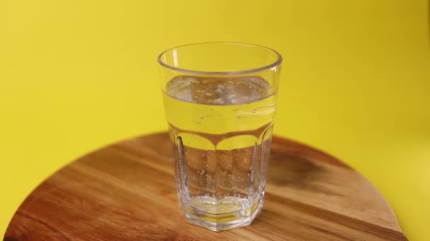 Burbujas Agua Mineral Vidrio Transparente Sobre Fondo Amarillo Mesa Madera — Vídeos de Stock