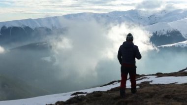Yürüyüşçü ve köpekler sisli bir günde kışın dağlarda manzaranın tadını çıkarıyorlar.