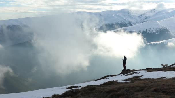 霧の多い日には冬の山の景色を楽しむハイカーや犬 — ストック動画