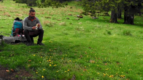 一个徒步旅行者在山林边吃草 — 图库视频影像