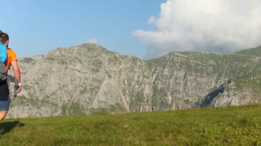 Sırt çantalı bir yürüyüşçü yazın kayalık dağda yürüyor.