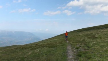 Yazın dağda yürüyen sırt çantalı yalnız bir yürüyüşçü.