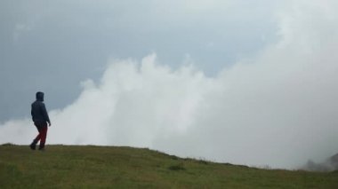Bir yürüyüşçü, sisli bir günde güzel bir dağ manzarasını izler ve hayran kalır.