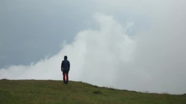 Bir yürüyüşçü, sisli bir günde güzel bir dağ manzarasını izler ve hayran kalır.