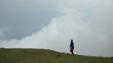 Bir yürüyüşçü, sisli bir günde güzel bir dağ manzarasını izler ve hayran kalır.