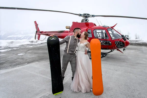 Novia Novio Besándose Sobre Fondo Helicóptero Invierno Con Tablas Snowboard Imagen de archivo