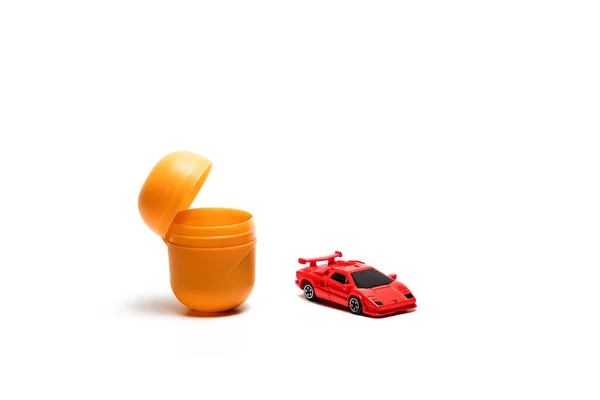 Open yellow egg kinder surprise with toy car lies on a white background