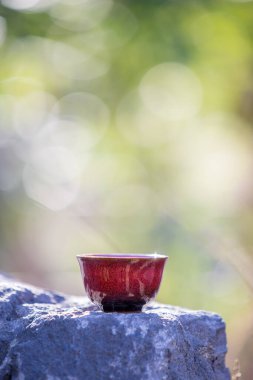 Çay seremonisi için kırmızı bir bardak çimlerin arasından geçen bir taşın üzerinde duruyor.