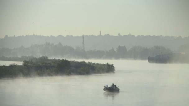 Чоловік на надувному човні сидить і кидає в воду кружляючий або рибальський стрижень посередині озеро або річка . — стокове відео