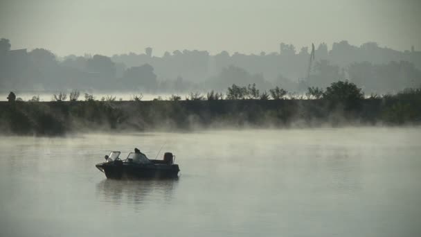 O homem em um barco inflável senta-se e joga uma haste de giro ou de pesca na água no meio de um lago ou rio. — Vídeo de Stock
