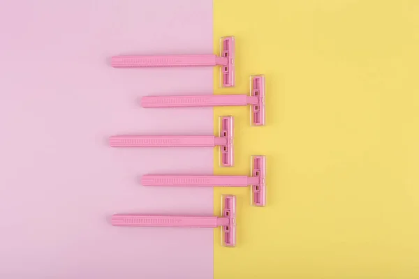 Pink razors on colored pink and yellow background — Stock Photo, Image