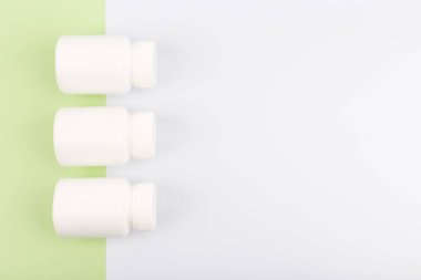 Açık yeşil ve beyaz arka planda üç ilaç şişesinin üst görünümü ve metin için boşluk