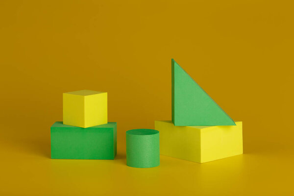 Геометрический натюрморт с желтыми и зелеными фигурами на темно-желтом фоне