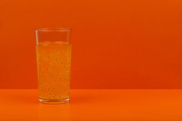 Fruktjuice med passionsfrukt frö på orange bakgrund med utrymme för text — Stockfoto