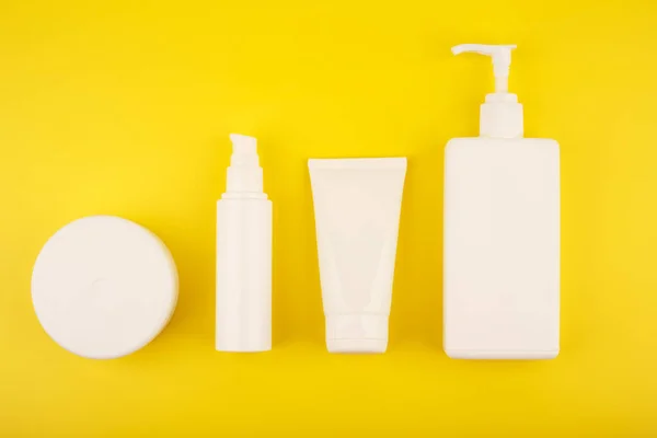 Colocação plana com conjunto de produtos cosméticos para cuidados com a pele e o corpo no fundo amarelo brilhante — Fotografia de Stock