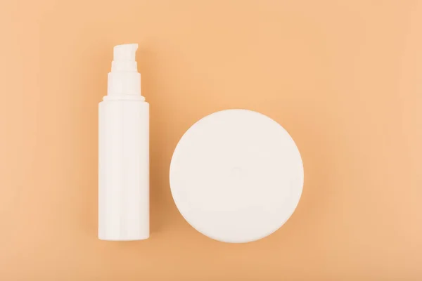 Flat lay with face and body cream in white jars on beige background. Concept of skin and body care — Stock Photo, Image