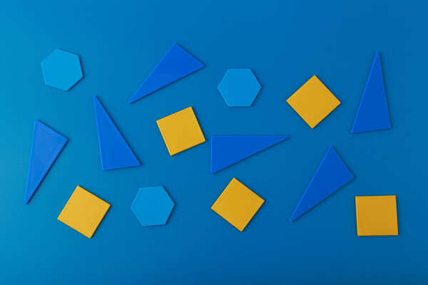 Flat lay with blue and yellow geometric figures on blue background