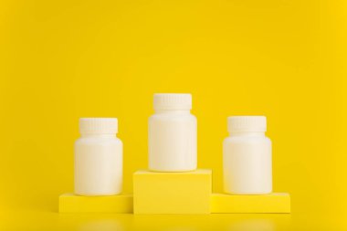 Sarı kaide üzerine beyaz ilaç şişeleri sarı arka plana karşı metin için yeri var. Eczane kavramı 