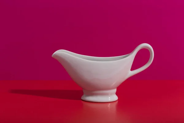 Barco de salsa de cerámica blanca sobre fondo creativo rojo y rosa con espacio para texto —  Fotos de Stock