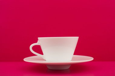 Beyaz seramik kahve fincanı pembe arka planda fotokopi alanı ile birlikte.
