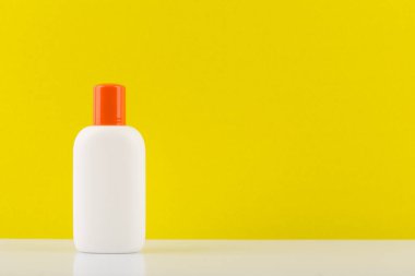 Beyaz masadaki güvenli bronzlaşma için güneş kremi kopyalama alanı olan sarı arkaplana karşı